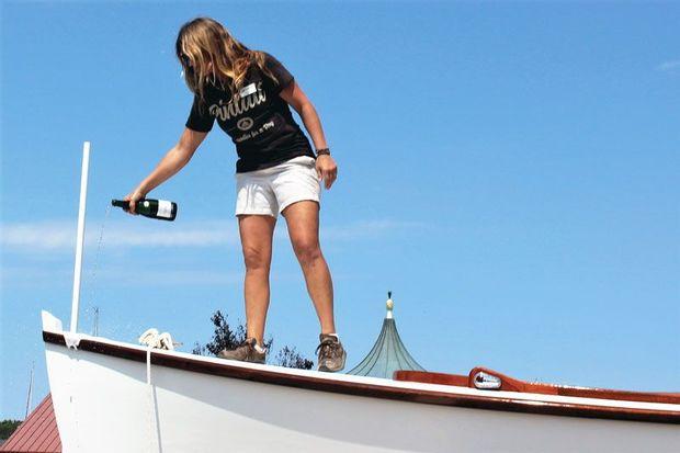 Boat yard program manager Jenn Kuhn christens Pintail in the traditional way with champagne.