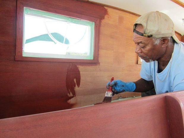 Peany Matthews applies stain to the interior of the wheel house on a Wiley 40 at Hartge Yacht Yard in Galesville, MD.