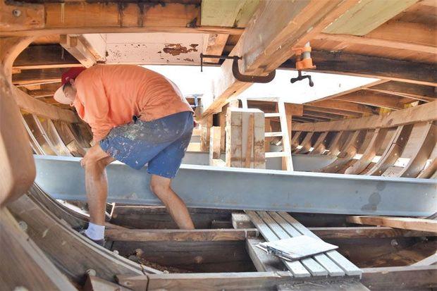 Shipwright Apprentice Spencer Sherwood helps slide a steel beam through 1889 Edna E. Lockwood at the Chesapeake Bay Maritime Museum in St. Michaels, MD. The beams were used to lift the topsides off the hull.