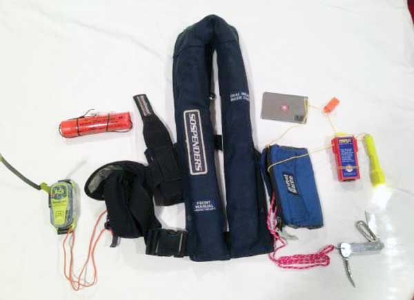 An inflatable PFD with personal equipment: PLB, streamer, mirror (for signaling), whistle, strobe light, flashlight, and knife. Perhaps add personal pen flares for offshore passages. Photo courtesy Kip Louttit