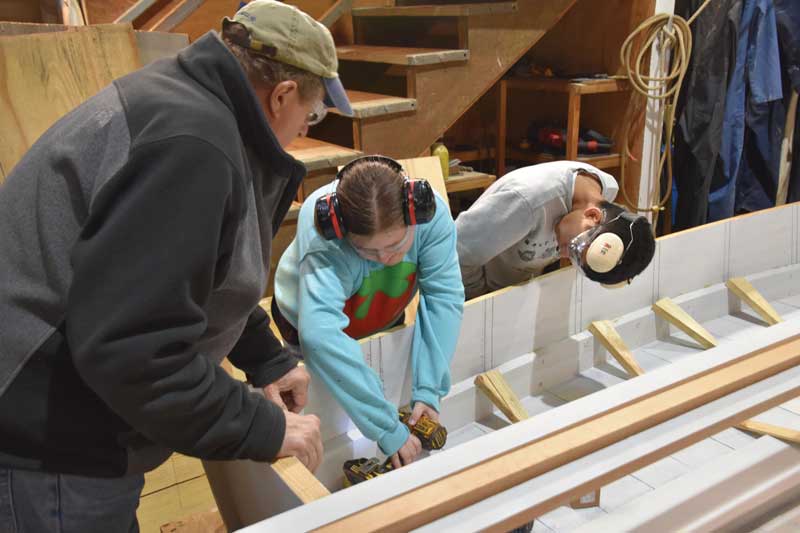Rising Tide volunteer Ned Henninghausen supervises program participants Ava Reid and Jonathan Storch working on the 17-foot skiff Mary at the Chesapeake Bay Maritime Museum’s shop in St. Michaels, MD.